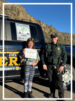 Deputy Stroup with Lottie in front of patrol truck with art 